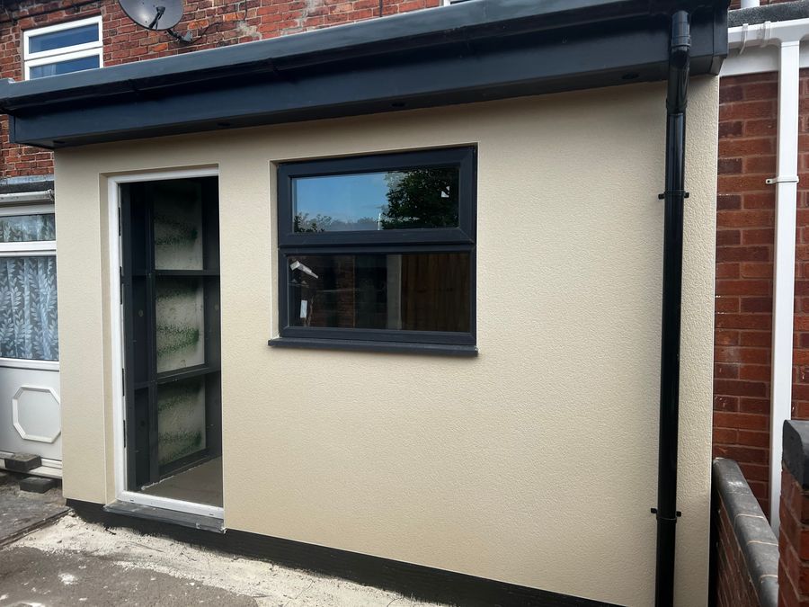 Finished flat-roof modular extension in cream render with dark-framed windows