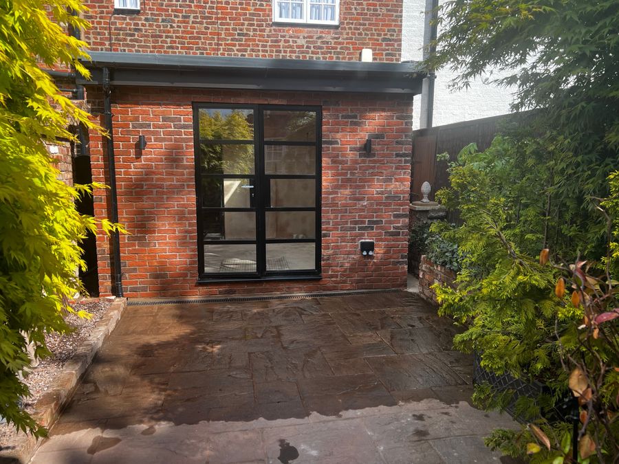 Brick rear extension with dark-framed glazed door on a terraced home