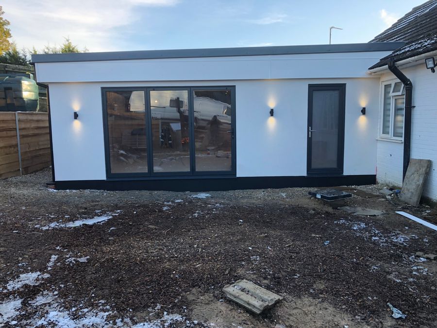 White garden room with black trim, sliding doors and exterior wall lights