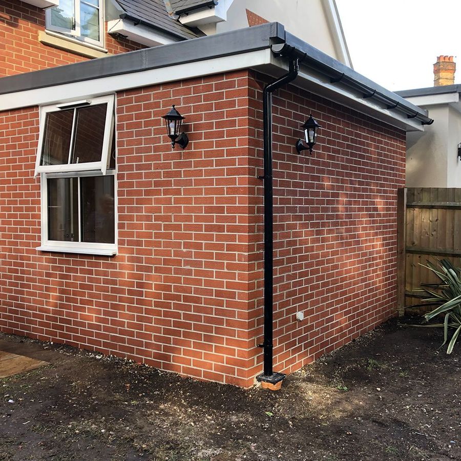 Brick-built modular extension corner with white uPVC window and exterior wall lights